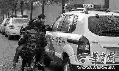 警车被贴上违停的罚单,骑车的路人觉得很好奇 本报记者 张杰 摄